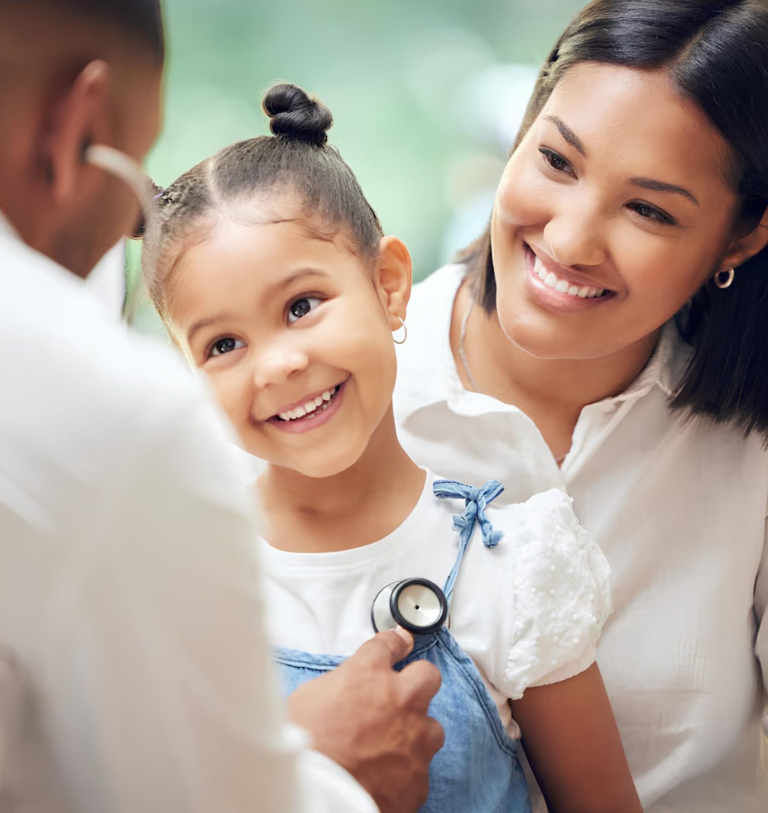 Mãe sorrindo enquanto filha é examinada pelo pediatra com estetoscópio